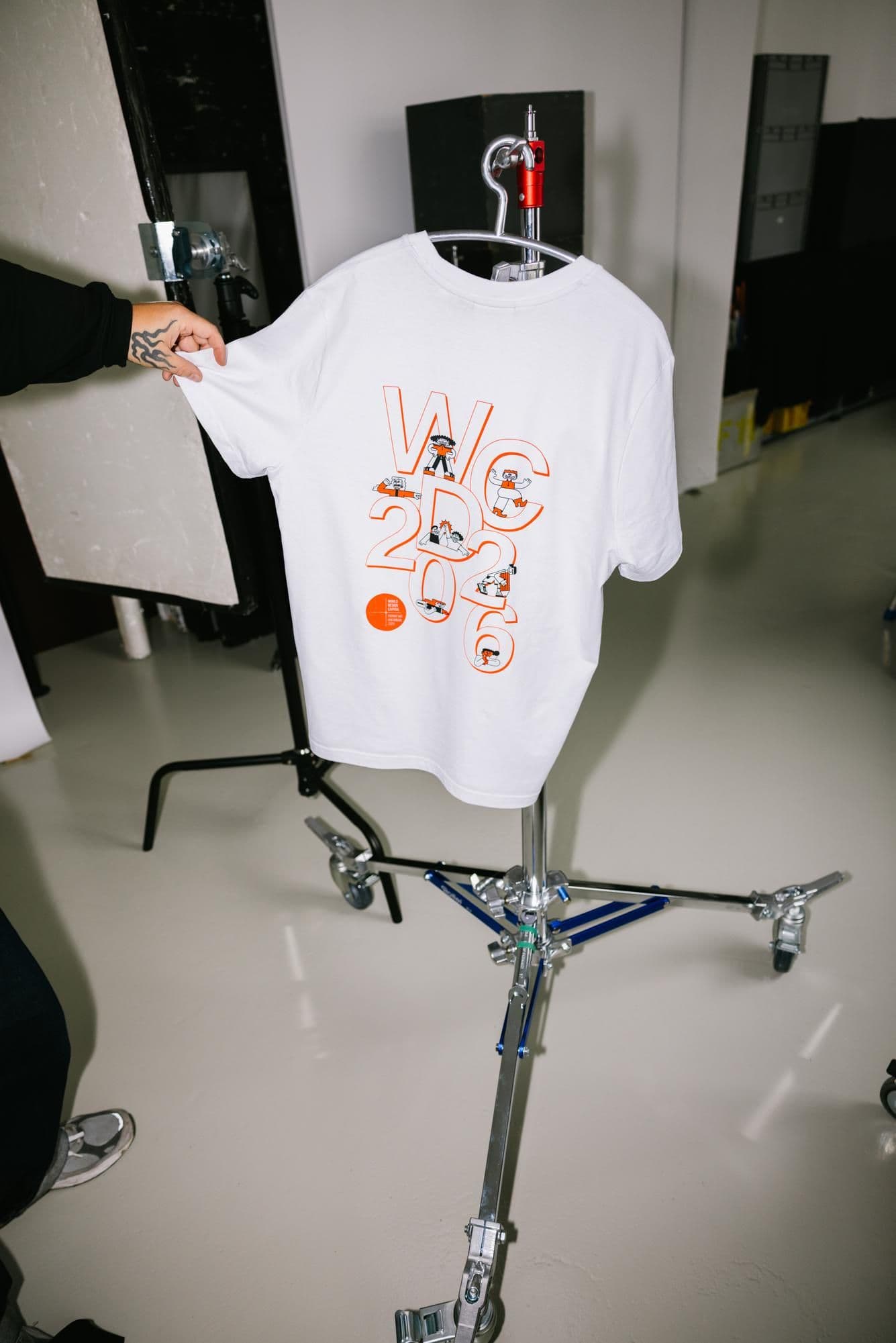 Eine Person präsentiert ein T-Shirt mit WDC-Grafiken.